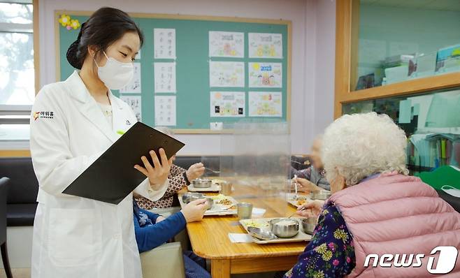 아워홈 영양사가 서울 마포구에 위치한 한서데이케어센터에서 ‘인지기능개선 관리 식단’을 시설 이용 어르신에게 소개하고 있다.(아워홈 제공)