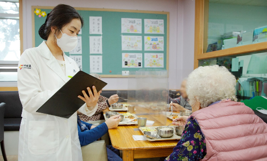 아워홈 영양사가 서울 마포구에 위치한 한서데이케어센터에서 '인지기능개선 관리 식단'을 시설 이용 어르신에게 소개하고 있다. [사진제공=아워홈]