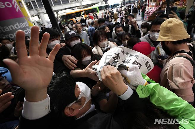 [도쿄=AP/뉴시스] 일본팀이 미국팀을 꺽고 제5회 월드베이스볼 클래식(WBC)을 제패한 뉴스를 실은 요미우리 신문의 호외가 22일 도쿄 시내에서 배포되자 행인들이 몰려 앞다퉈 받아가고 있다.  2023.03.22