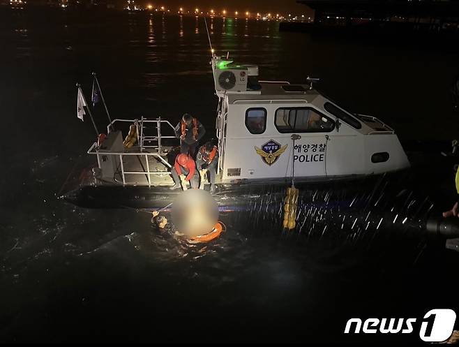 23일 오전 3시58분께 부산 감천항 인근 해상에 빠진 차량에서 자력으로 빠져나온 30대 여성을 해경이 구조하고 있다.(부산해경 제공)