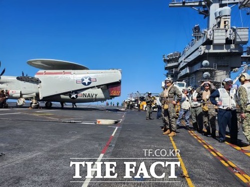 미 해군 항공모함 니미츠함에 주기된 E-2 조기경보기 옆에 항모 승조원들이 서 있다./합동참모본부