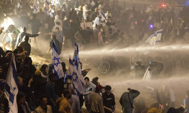 시위대 향해 물대포 발사 이스라엘 경찰이 27일(현지시간) 텔아비브에서 고속도로를 막은 채 베냐민 네타냐후 정부의 사법개편안 반대 시위를 벌이고 있는 시민들을 해산하기 위해 물대포를 쏘고 있다. AP연합뉴스
