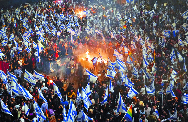 베냐민 네타냐후 이스라엘 총리가 이끄는 극우 연정의 사법 개혁에 반대하는 시민들이 지난 26일(현지시간) 텔아비브의 한 고속도로에서 국기를 흔들며 시위를 벌이고 있다. 이날 이스라엘 총리실이 사법 개혁을 공개 비판한 요아브 갈란트 국방장관을 해임한다고 발표하자 시위는 더 격렬해졌다. AP연합뉴스