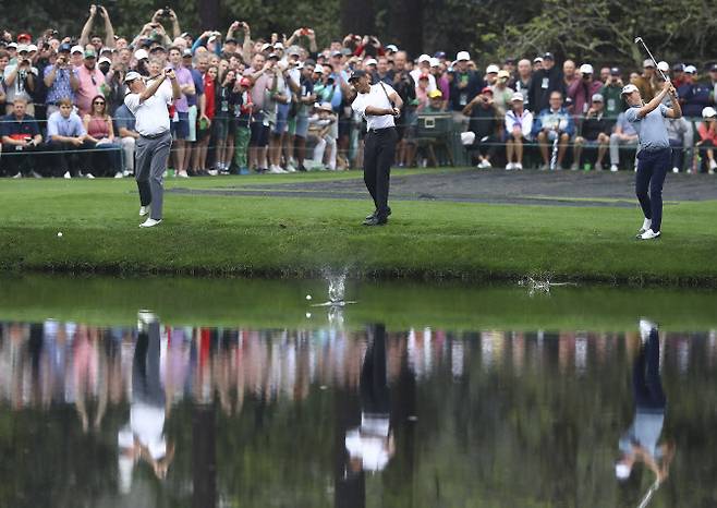오거스타 내셔널 골프클럽 16번홀에서 프레드 커플스(왼쪽부터)와 타이거 우즈, 저스틴 토머스가 물을 향해 공을 치는 이른바 ‘물수제비샷’을 하고 있다. (사진=AFPBBNews)