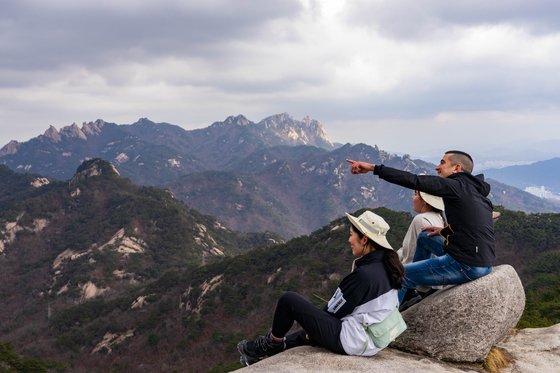 젊은 등산객들이 영봉 인근 너럭바위에 앉아 북한산 정취를 즐기고 있다.