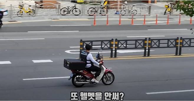한 오토바이 배달 기사가 헬맷 미착용 상태로 도로를 달리고 있다. 이 남성은 곧 경찰에 신고 당해 범칙금을 부과받게 된다. /유튜브 캡처