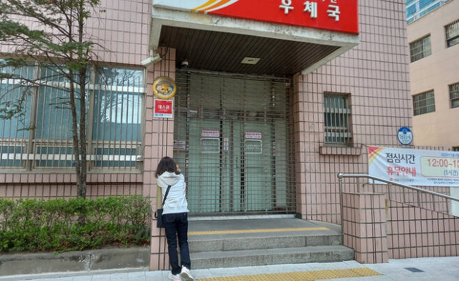 지난달 31일 정오쯤 서울의 한 우체국 앞에 ‘점심시간 휴무제’를 모르고 온 시민이 운영 재개를 기다리고 있다.