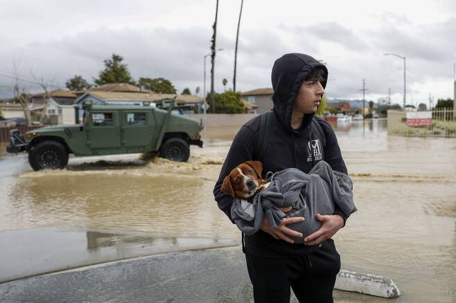 홍수 피해를 본 미국 캘리포니아주 몬터레이 지역 주민이 지난달 12일(현지 시각) 반려견을 안고 집을 떠나 대피하고 있다. /연합뉴스