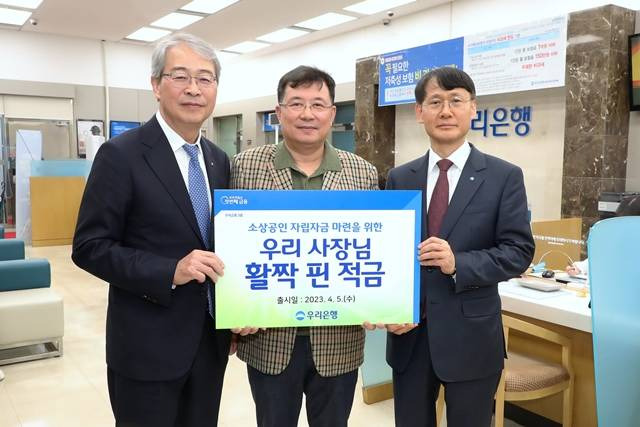 우리금융그룹 임종룡 회장(왼쪽)과 우리은행 정연기 중소기업그룹 부행장(오른쪽)이 소상공인 상생금융상품 '우리 사장님 활짝 핀 적금' 1호 가입 고객과 기념촬영을 하고 있다. /우리금융