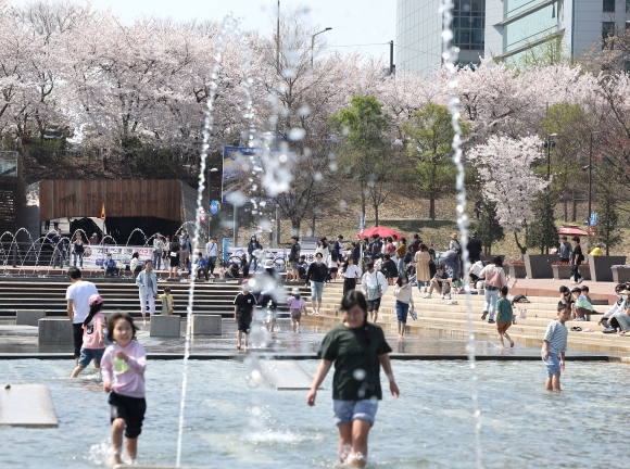 벚꽃 한창, 벌써 더위 - 서울 낮 기온이 최고 26도까지 오르며 더운 날씨를 보이는 2일 오후 벚꽃이 활짝 핀 여의도 물빛광장에서 어린이들이 물놀이를 즐기고 있다. 2023.4.2 연합뉴스