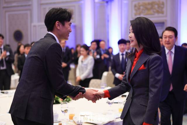 지난달 23일 청와대 영빈관에서 열린 복지·노동 현장 종사자 초청 오찬에서 김건희 여사가 한 참석자와 악수하고 있다. 김 여사 뒤로 윤석열 대통령이 초점이 나간 채로 찍혔다.사진=대통령실