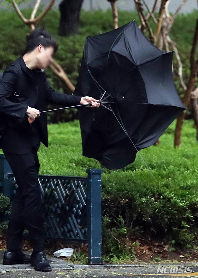 [서울=뉴시스] 김진아 기자 = 수도권 등 전국 대부분 지역에 강풍특보가 내린 11일 서울 종로구 일대에서 한 시민의 우산이 뒤집히고 있다.2023.04.11. bluesoda@newsis.com