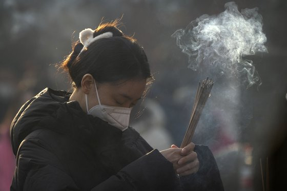 지난 1월 중국 베이징 융허궁에서 향을 피우며 기도하는 한 여성의 모습. AP=연합뉴스