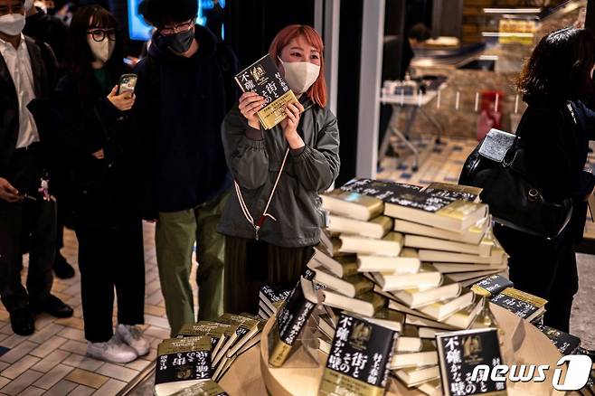 13일 발매된 무라카미 하루키의 신작 소설을 손에 든 팬이 기념 사진을 찍고 있다. ⓒ AFP=뉴스1 ⓒ News1 권진영 기자