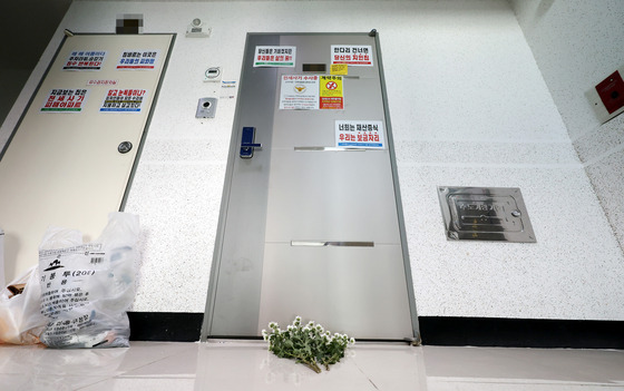 Flowers in front of an apartment door in Michuhol District, Incheon, on Monday lament a former tenant of the apartment who committed suicide after jumping from the apartment at 2 a.m. In a suicide note, the tenant apologized to her family of being the victim of a long-term rent deposit scam. This is the third suicide connected to the scam. [YONHAP]