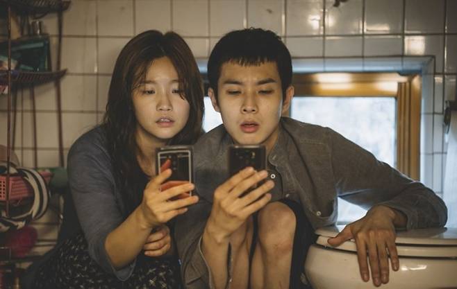 A movie still of "Parasite" depicting Park So-dam (left) and Choi Woo-sik as family members living in a semibasement, or "banjiha" residence in Seoul. (CJ ENM)