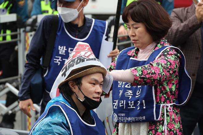 ‘420발달장애인 권리보장 촉구대회’와 ‘발달장애인 전 생애 권리기반 구축 촉구 전국장애인부모연대 전국집중결의대회’에서 한 참석자가 다른 참석자의 머리에 구호가 적힌 작은 펼침막을 둘러주고 있다. 김혜윤 기자