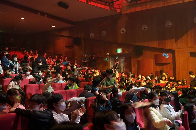 Students from Yeomdong Elementary School throw paper airplanes during a performance of “Joyful Island” by Band Sinsum, at the Guro Arts Valley in Seoul, on Friday. (Spring Day)