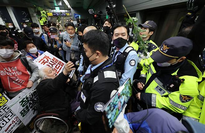 박경석 전국장애인차별철폐연대(전장연) 대표가 지난 21일 오전 서울 지하철 5호선 광화문역에서 탑승 시위 중 지하철 탑승을 저지 당하자 국화꽃을 던지고 있다. [사진 출처 = 연합뉴스]