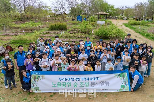 우리은행은 지난 23일 마포구 상암동 소재 노을공원에서 숲 조성 봉사활동을 실시했다. 참여한 임직원 및 가족들이 묘목을 들고 기념촬영을 하고 있다. (사진=우리은행)