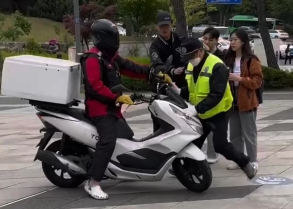 지난 25일 서울 연세대학교 백양로 정문 인근에서 오토바이를 탄 배달기사가 경비원을 들이받자 주변 학생들이 말리고 있다. 제보자 제공 영상 캡처