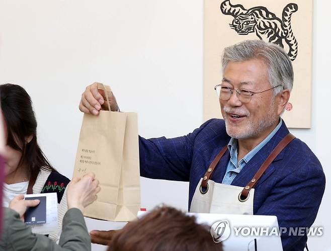 문 전 대통령 "책 여기 있습니다" (양산=연합뉴스) 김동민 기자 = 문재인 전 대통령이 26일 오후 경남 양산시 하북면 자신의 책방 '평산책방'에서 계산 업무를 하며 책을 손님에게 건네고 있다. 2023.4.26 image@yna.co.kr