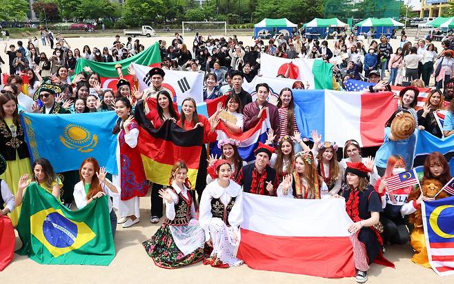 Participants in traditional costumes and holding flags from their respective countries of origin pose for photos during the 17th Culture Expo event hosted by the Korean Language and Culture Education Institute at Hankuk University of Foreign Studies in Dongdaemun-gu, Seoul Friday. Foreign exchange students participated in the Culture Expo, operating booths introducing regional cultures, and conducting traditional music and dance performances. (Yonhap)