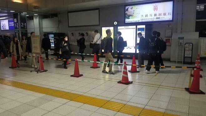 일본 도쿄 오사키역에서 지난 4월 24일 퇴근한 시민들이 가로분리봉을 따라 한 줄로 플랫폼으로 향하고 있다.&nbsp;이 역에서는 승객이 한꺼번에 몰려 병목현상이 벌어지는 것을 막기 위해 퇴근 시간대에는 가로분리봉을 설치해 시민 이동을 유도하고 있다. 도쿄=강구열 특파원