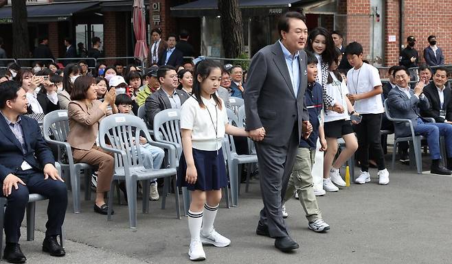 윤석열 대통령과 김건희 여사가 4일 서울 용산 대통령실 앞마당에 조성된 용산 어린이정원 개방행사에서 개문 퍼포먼스를 하기 위해 어린이들과 함께 단상에 오르고 있다. 대통령실사진기자단