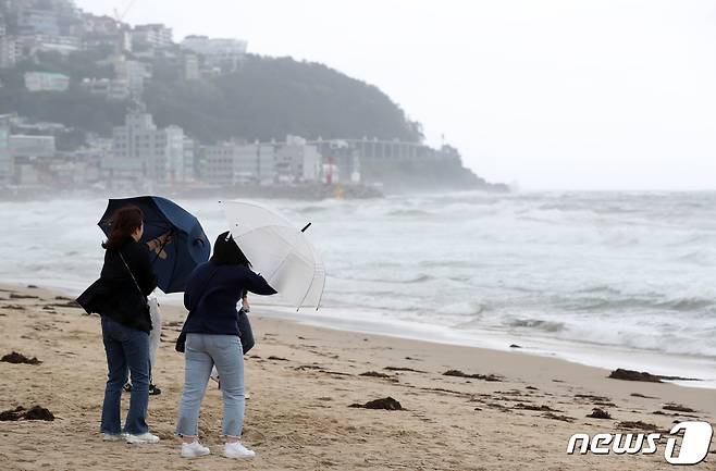 부산에 호우·강풍특보가 내려진 5일 부산 해운대해수욕장을 찾은 관광객들이 강한 비바람에 우산을 부여잡고 있다. 2023.5.5/뉴스1 ⓒ News1 윤일지 기자