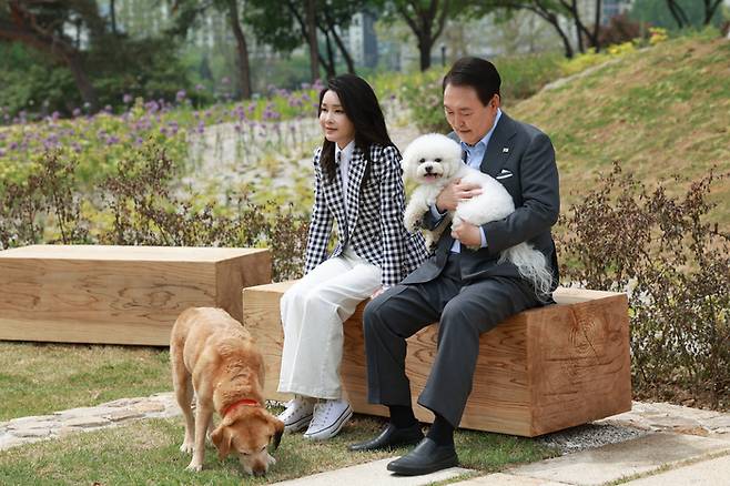 윤석열 대통령과 부인 김건희 여사가 4일 서울 용산 대통령실의 앞마당에 조성된 용산 어린이정원 개방 기념식수를 마친 뒤 써니와 은퇴안내견 새롬이(왼쪽)와 휴식을 취하고 있다.  대통령실 제공