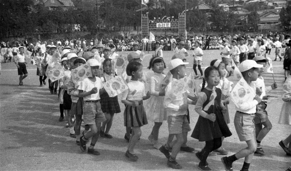 베이비붐 시대의 운동회 풍경 - 1963년 한 국민학교에서 열린 가을운동회에 많은 어린이들이 태극기를 들고 줄지어 걷고 있다. 이 시기는 전후 베이비붐 시기로 학교나 동네 어디에서든 아이들의 웃음과 울음 소리가 울려퍼졌다. 1962. 10 서울신문 사진창고