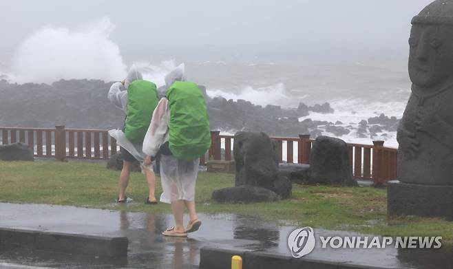 비바람 몰아치는 제주 해안 (서귀포=연합뉴스) 박지호 기자 = 제주에 호우특보가 내려진 4일 오전 제주 서귀포시 사계해안도로에서 우비로 무장한 배낭여행객이 걷고 있다. 2023.5.4 jihopark@yna.co.kr