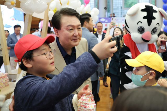 윤석열 대통령이 5일 청와대 연무관에서 열린 어린이날 초청행사에서 팝콘을 나눠주며 아이들과 셀카를 찍고 있다.  대통령실 제공