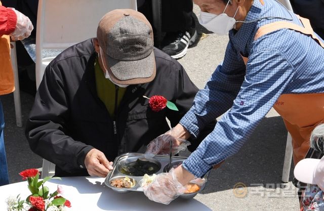 어버이날인 8일 서울 동대문구 다일공동체 밥퍼나눔운동본부 마당에서 열린 '밥퍼와 함께하는 어버이날 효도잔치' 행사장을 찾은 어르신들이 카네이션을 가슴에 달고 점심식사를 받고 있다.