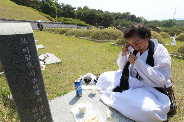 광주 북구 국립 5·18 민주묘지에서 유족이 가족 열사의 묘소 앞에서 눈물을 훔치고 있다. 연합뉴스