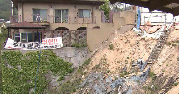 붕괴 공사 현장 바로 옆 단독 주택 주민들은 현수막을 내걸며 '2차 붕괴 위험'을 호소하고 있다. [사진=SBS NEWS 보도화면 갈무리]