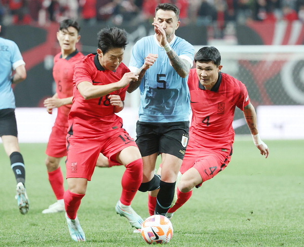 지난 3월 28일 열린 한국과 우루과이의 축구 평가전에서 이강인(왼쪽)과 김민재가 상대 선수의 공을 빼앗고 있다. 연합뉴스