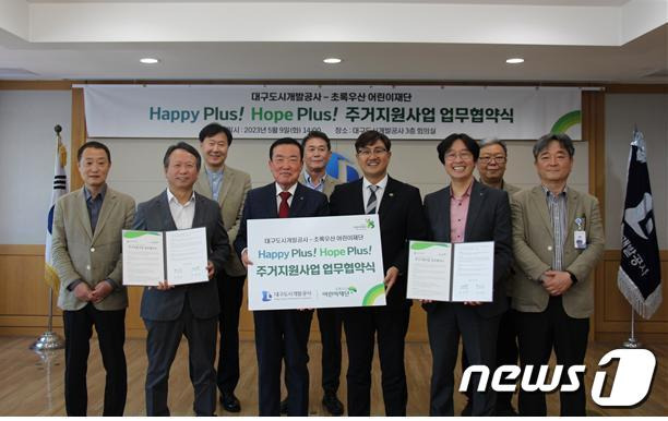 정명섭 대구도시개발공사장(왼쪽 세번째)과 문희영 초록우산 어린이재단 대구지역본부장(오른쪽 세번째)이 주거빈곤아동을 위한 주거지원사업 업무협약을 체결한 뒤 협약서를 펼쳐보이고 있다.(대구도시개발공사 제공)