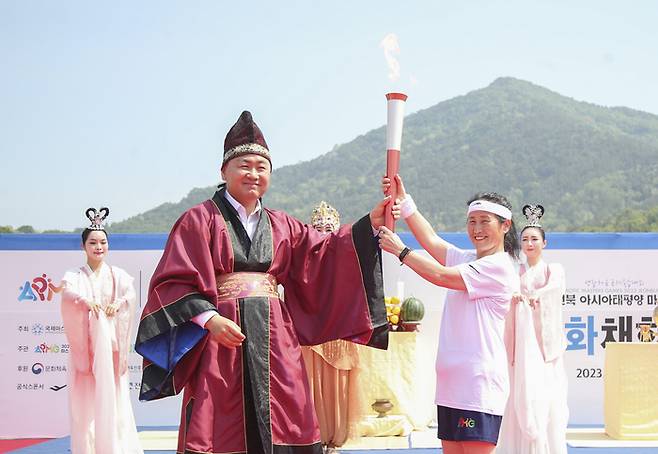 2023 전북 아시아·태평양 마스터스대회 성화 채화식이 11일 전북 익산 미륵사지에서 열린 가운데 김관영 도지사가 대회참가자 중 익산지역 최고령자인 김영순씨에게 성화를 전달하고 있다. 전북도 제공