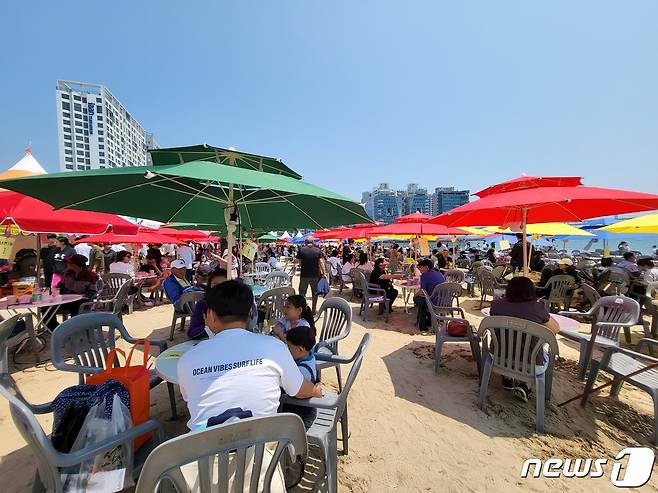 ‘제21회 광안리어방축제’를 찾은 시민들이 먹거리 부스 앞에 설치된 파라솔에서 다회용기에 담긴 음식을 즐기고 있다.(독자 제공)