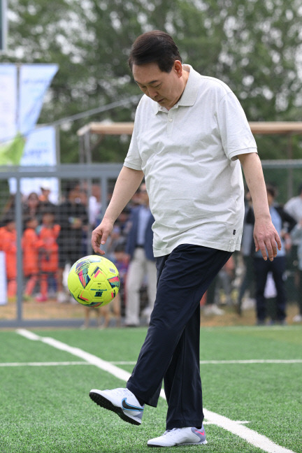 윤석열 대통령이 휴일인 14일 서울 용산 어린이정원 내 축구장에서  진행된 축구 클리닉에서 전국 유소년 축구대회에 참가한 어린이 선수들과 공다루기 시합을 하고 있다. 대통령실 제공