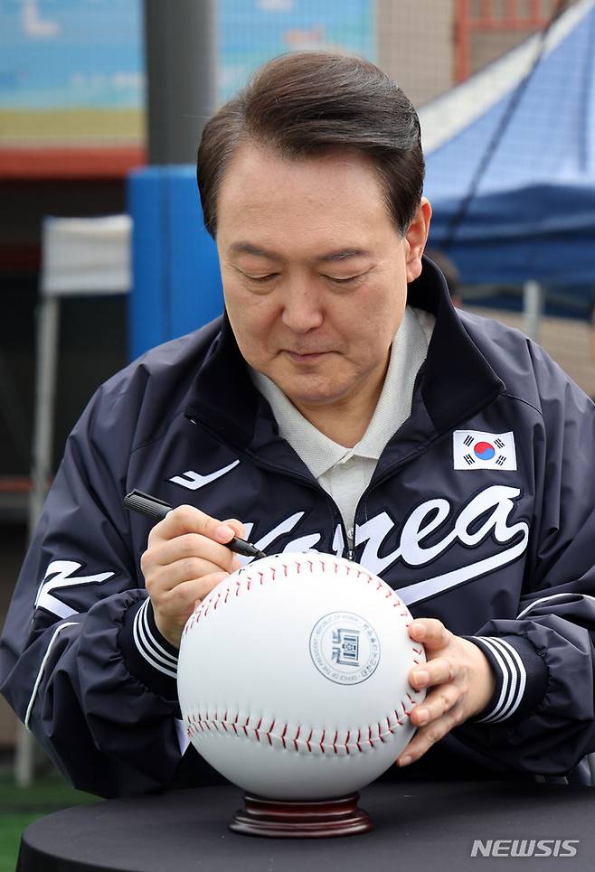 [서울=뉴시스] 전신 기자 = 윤석열 대통령이 14일 서울 용산어린이정원 내 야구장에서 열린 2023 대통령실 초청 전국 유소년 야구대회 결승 경기에 앞서 대형 야구공에 사인을 하고 있다. (대통령실통신사진기자단) 2023.05.14. photo1006@newsis.com