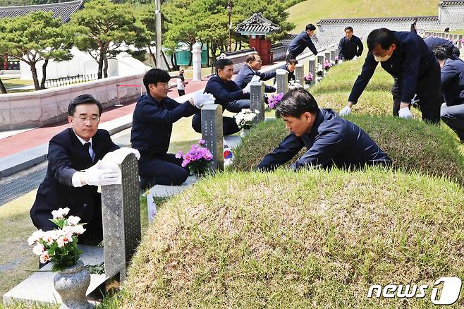 김성환 광주환경공단 이사장과 임직원들이 16일 국립5.18민주묘지를 찾아 참배하고 묘비를 닦고 있다.(광주환경공단 제공)2023.5.16/뉴스1