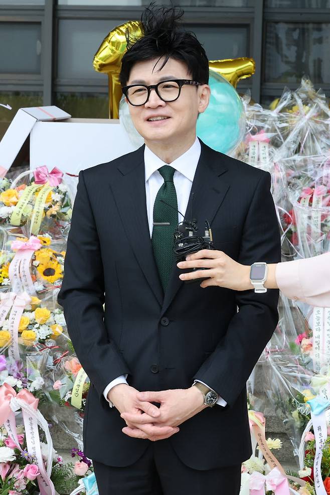 한동훈 법무부 장관이 취임 1년을 맞은 17일 오전 정부과천청사 법무부로 출근하며 소회를 묻는 기자의 질문에 답하고 있다. 이날 법무부 앞 계단에는 지지자들이 보낸 축하 꽃다발이 수북이 놓여 있었다 (사진=연합뉴스)