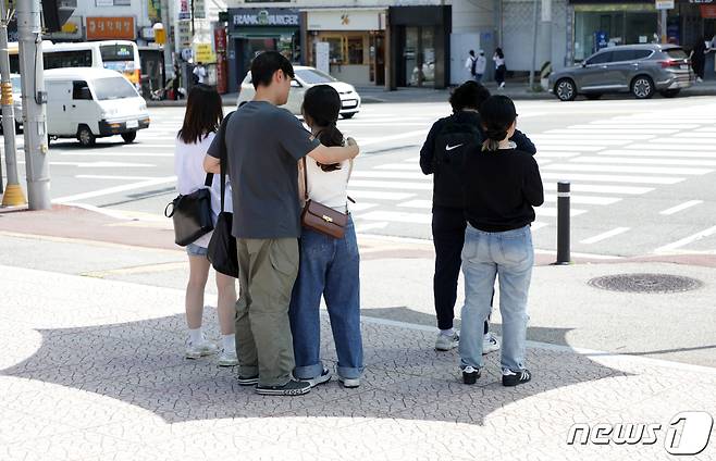 17일 오전 울산대학교 앞 신호등 대기 공간에 마련된 파라솔 아래서 대학생들이 햇빝을 피하고 있다.2023.5.17/뉴스1