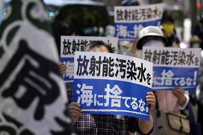 16일 일본 도쿄에 있는 도쿄전력(TEPCO) 본사 앞에서  시위대가 '방사능 오염수 방류 반대' 손팻말을 들고 후쿠시마 오염수 방류에 반대하고 있다. /AP=뉴시스