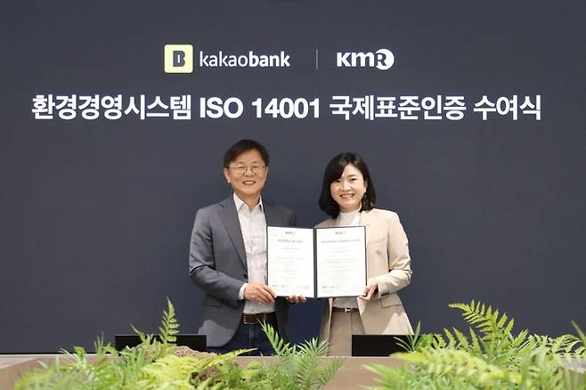 17일 성남시 분당구의 카카오뱅크 판교오피스에서 열린 ‘ISO 14001’ 인증서 수여식에서 카카오뱅크 이강원 최고 커뮤니케이션책임자(왼쪽)와 한국경영인증원 황은주 대표이사(오른쪽)가 기념 촬영하고 있다.