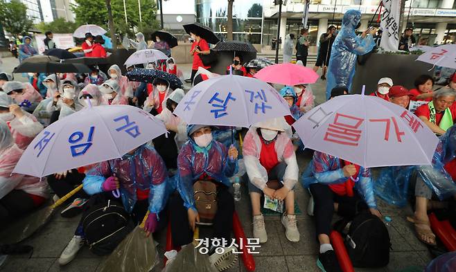 최저임금 12,000원 인상을 요구하는 청소노동자들이 18일 서울 중구 연세대학교세브란스빌딩 앞에서 우산을 쓰고 집회를 하고 있다. 김창길기자