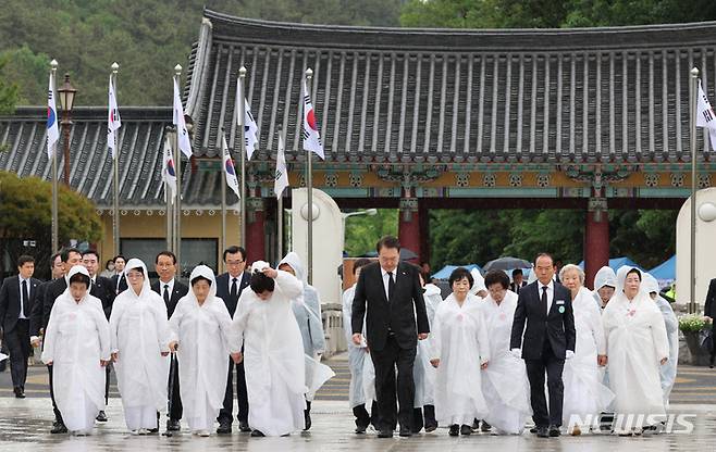 [광주=뉴시스] 홍효식 기자 = 윤석열 대통령이 18일 광주 북구 국립5·18민주묘지에서 열린 제43주년 5·18민주화운동 기념식에 오월어머니회 회원들과 함께 입장하고 있다. (대통령실통신사진기자단) 2023.05.18. yesphoto@newsis.com